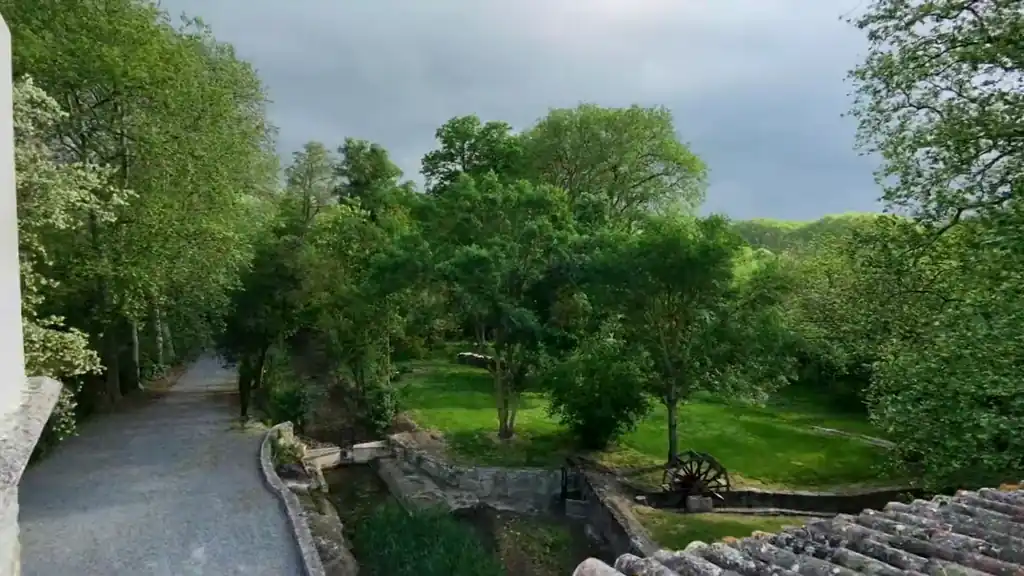 Filmed with a drone: over the edge of the roof to the garden, with the stone channel, the iron wheel and the trees.