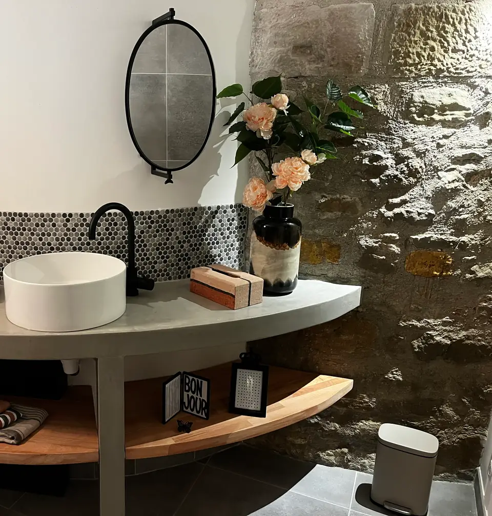 The WC: a round basin on a curved counter against the bare stone wall.