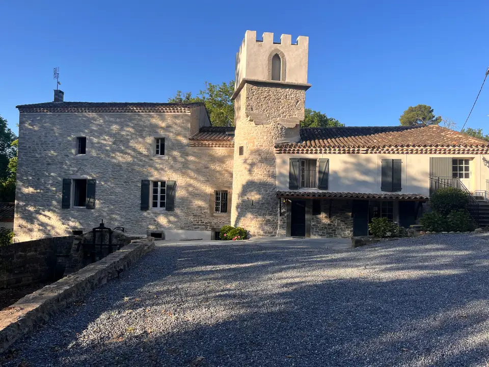 The mill from the gravel forecourt: the stone façade, the crenellated tower and the white wing.