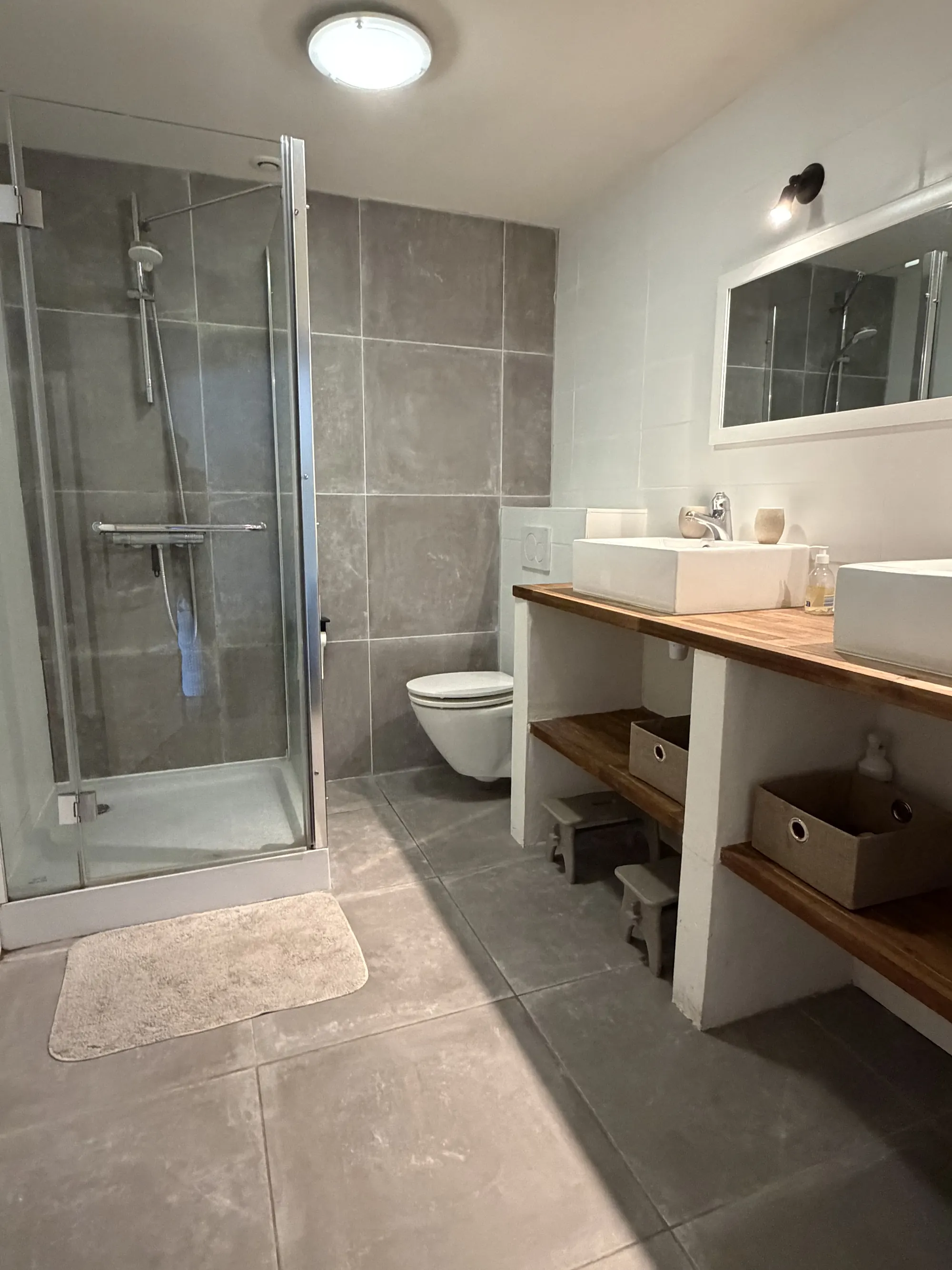 Een badkamer in grijze tegels met een douchecabine.