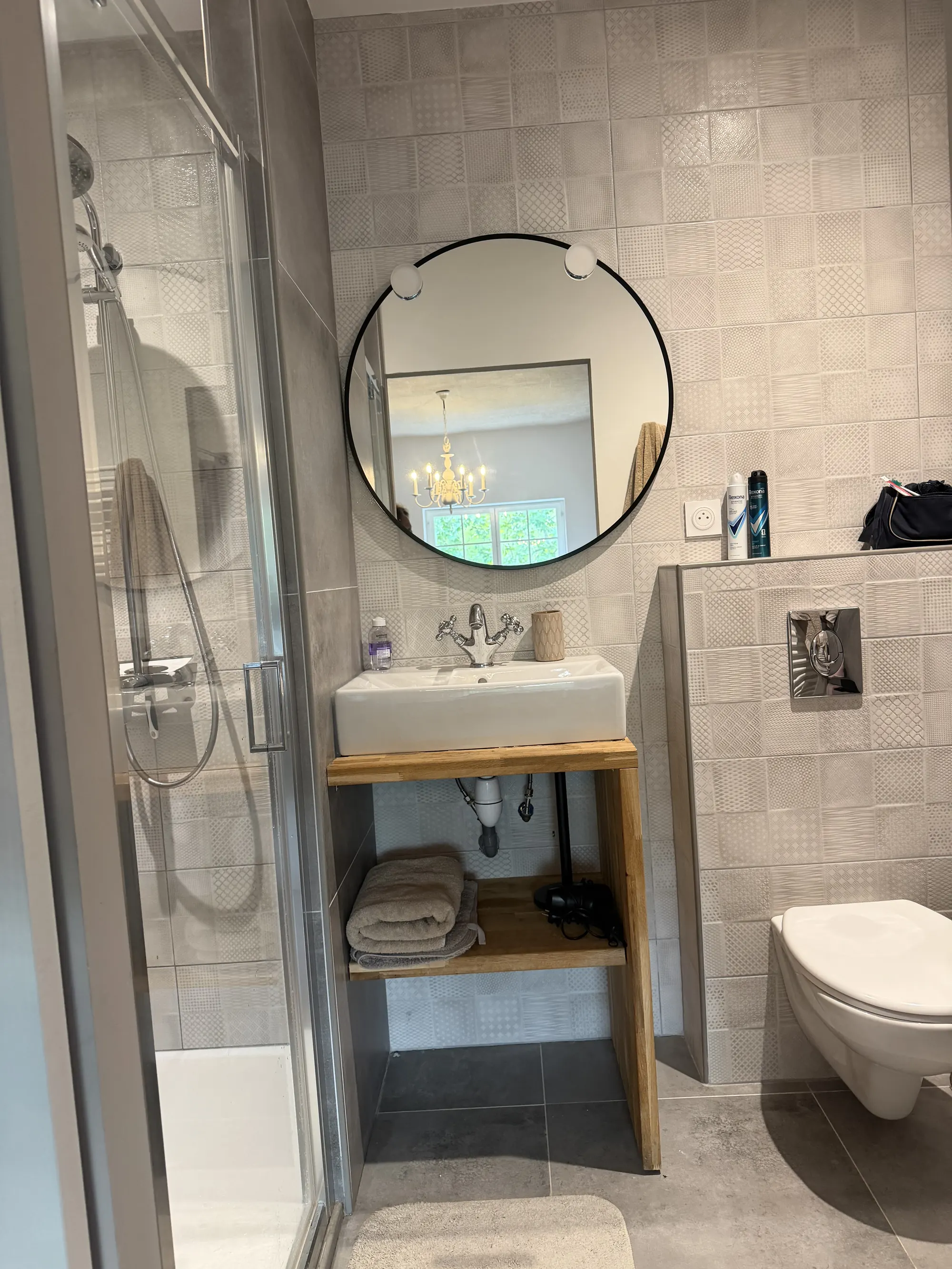 Een badkamer met een ronde spiegel en een douche.