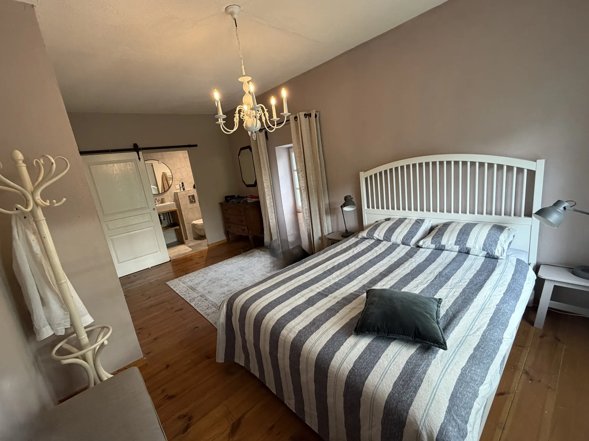 Een slaapkamer met gestreepte sprei en een deur naar de eigen badkamer.