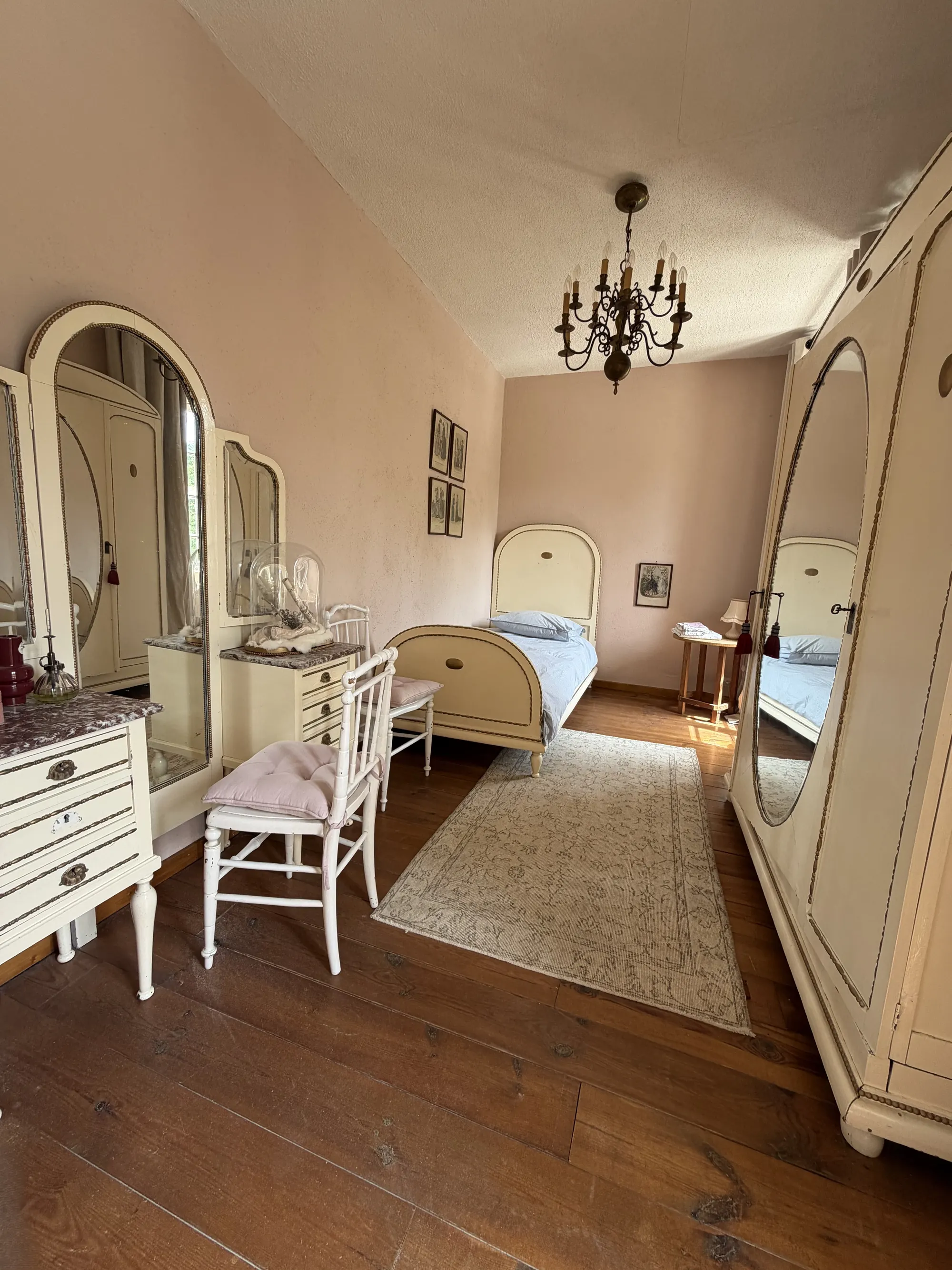 Een slaapkamer met eenpersoonsbed, kaptafel en spiegelkast.
